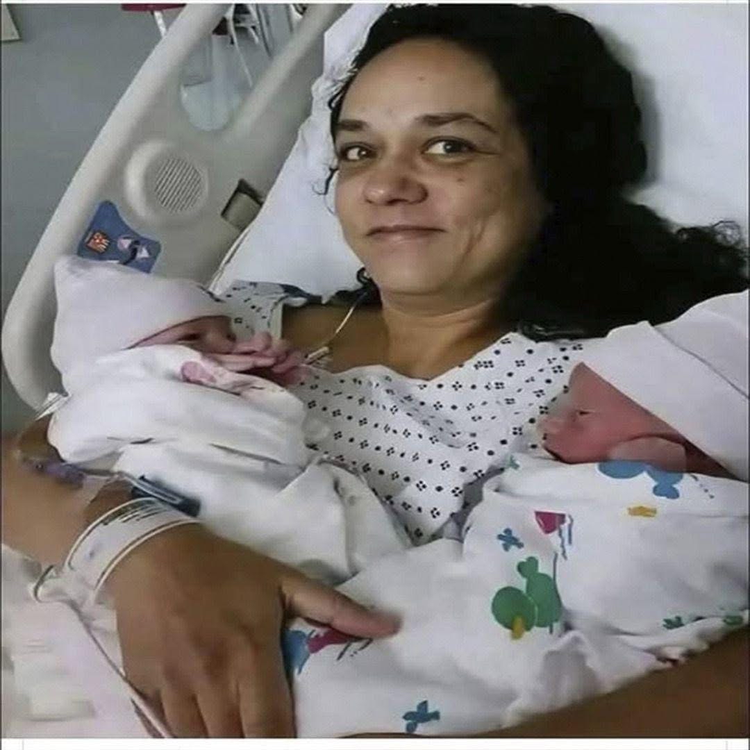 Mujer de 58 años sostiene a sus gemelos recién nacidos en el hospital, mostrando un momento de felicidad familiar.